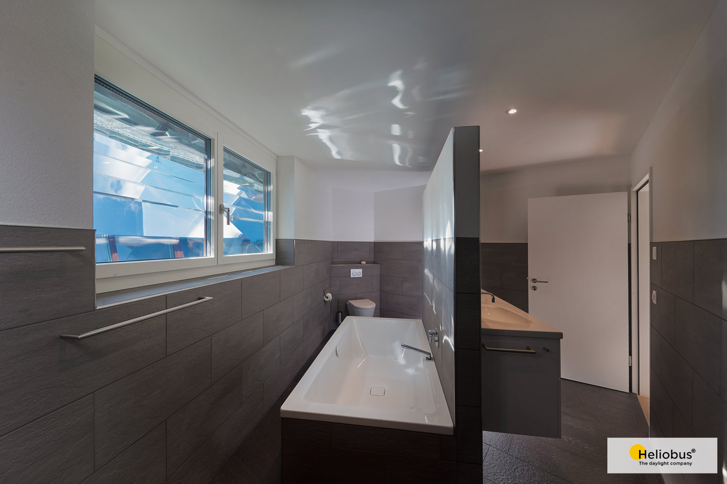 Innenaufnahme eines Untergeschoss Badezimmer, dass mit einem Lichtschacht Spiegelsystem von Heliobus für mehr Licht sorgt