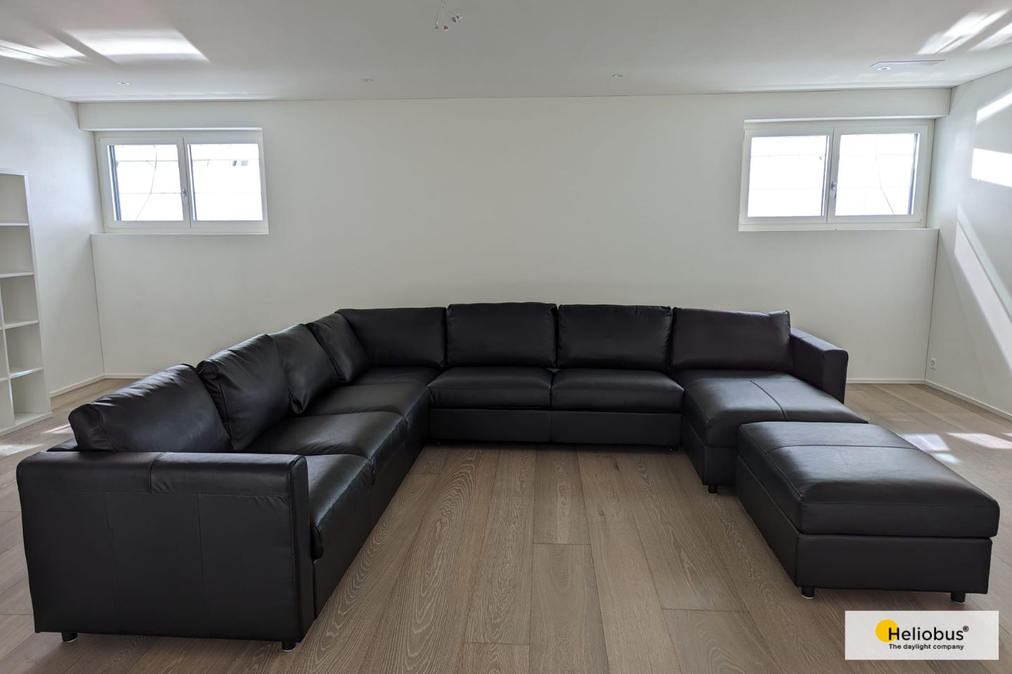 Sofa steht im Untergeschoss vor Wand mit zwei Fenstern voller Tageslicht